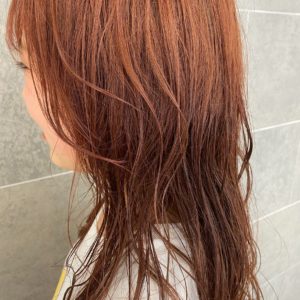 肩甲骨が隠れる程の長さの赤橙色のヘアスタイル