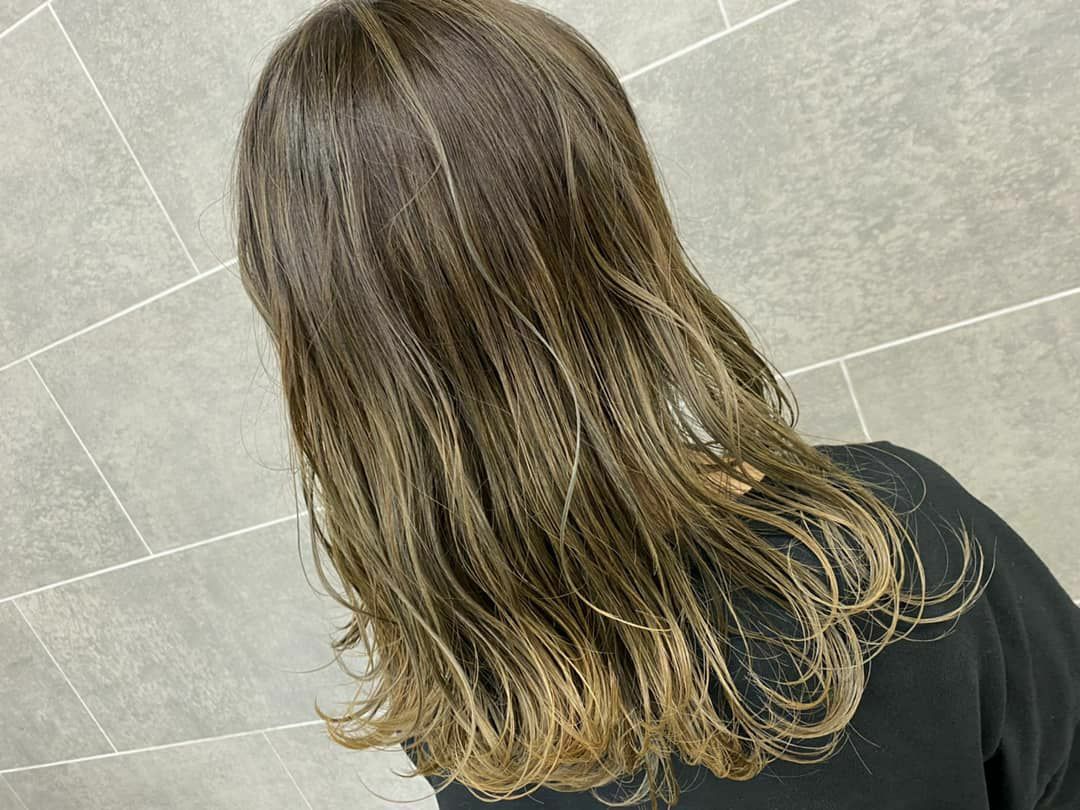 肩甲骨にかかる長さの毛先が明るく染められたヘアスタイル