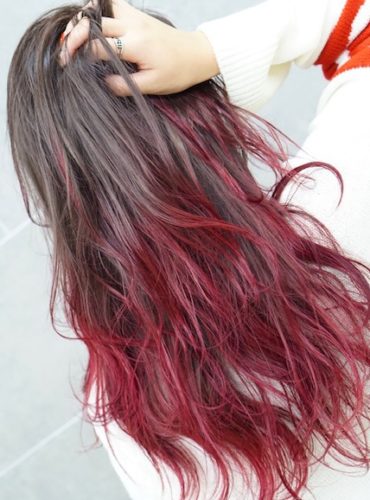 肩甲骨が隠れる程の長さの毛先が赤色のヘアスタイル