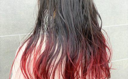 肩甲骨が隠れる程の長さの毛先が赤色のヘアスタイル