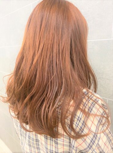 肩甲骨が隠れる程の長さの橙色のヘアスタイル