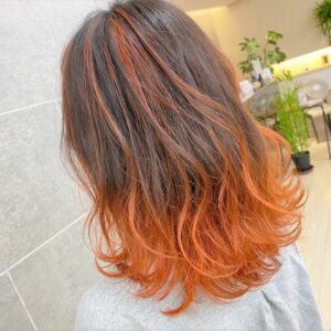 肩にかかる長さの部分的に橙色になっているヘアスタイル